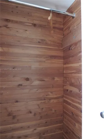 Horizontal wood-plank wall paneling and a metal garment rod