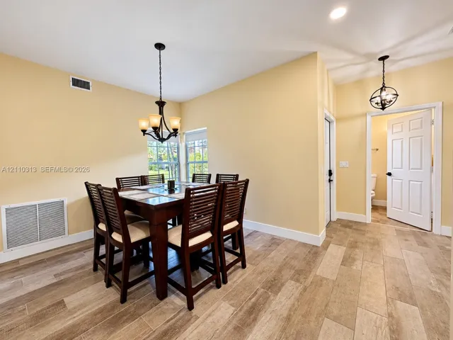 Wood-finish tile flooring, recessed lighting, and dual tiered chandeliers featuring multi-light fixtures