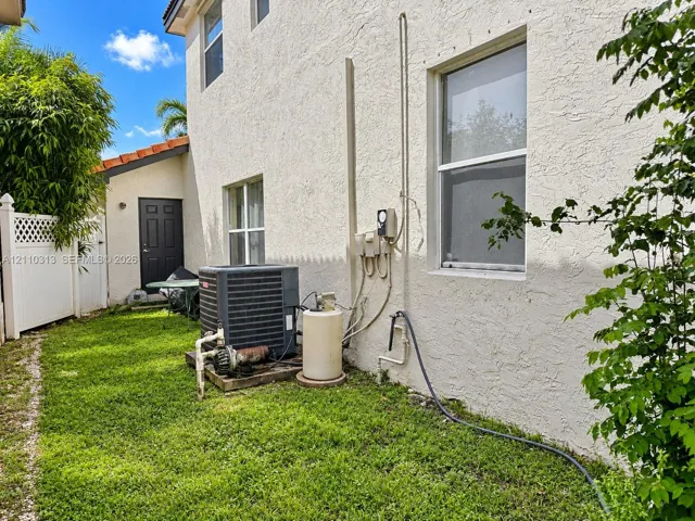 Stucco exterior featuring dual-pane windows, a tiled roofline, and white vinyl privacy fencing