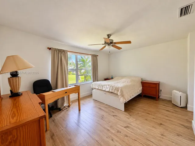 Bedroom featuring wood-finish flooring, a multi-blade ceiling fan, and a single-pane window
