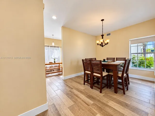 Wood-finish tile flooring, multi-pane windows, and a multi-light hanging chandelier