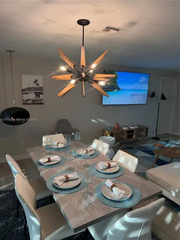 Mid-century modern starburst chandelier with wood-finish accents, wall-mounted suspended fireplace, and neutral wall color
