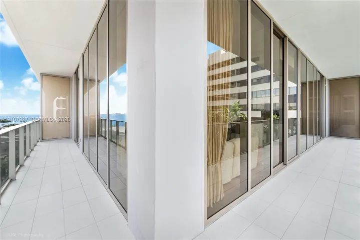 Wrap-around terrace featuring large-format tile flooring, floor-to-ceiling glass paneling, and metal railing