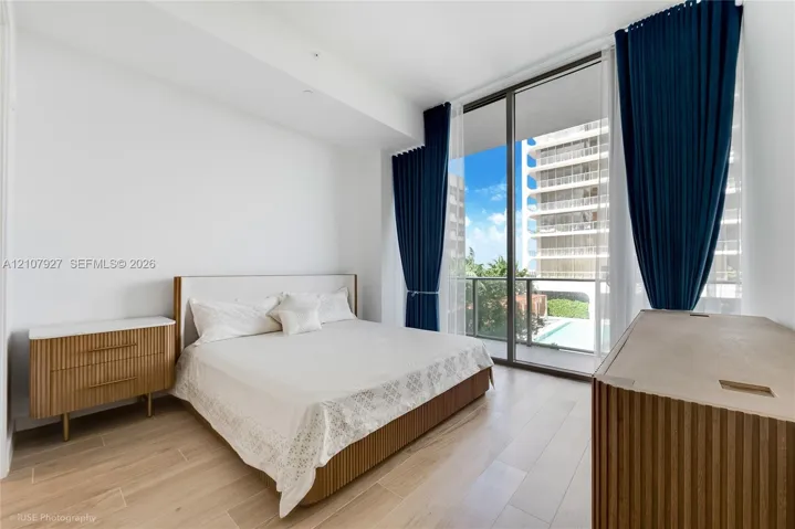 Floor-to-ceiling windows featuring access to a private balcony, wood-finish flooring, and neutral wall tones