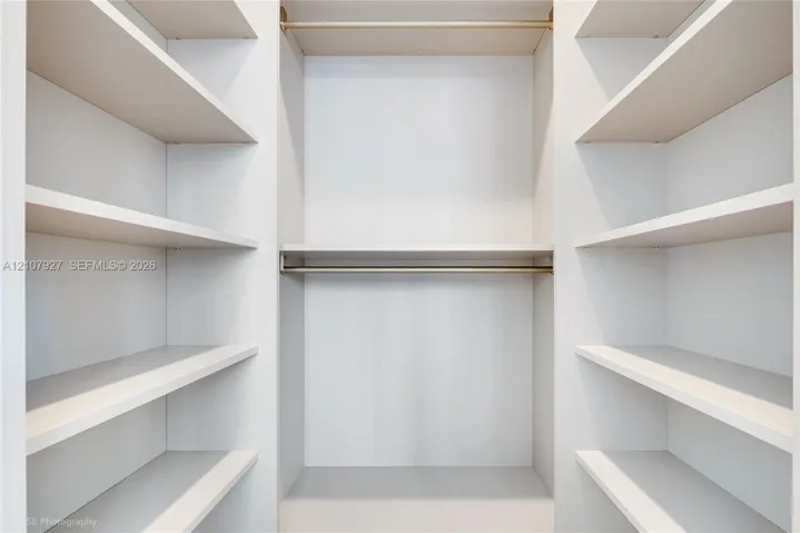 Custom closet featuring white built-in shelving and dual horizontal metal hanging rods