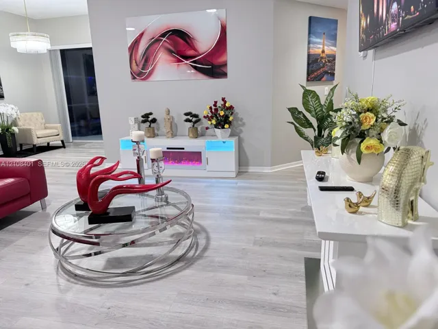 Light-toned wood-finish flooring, white media console with integrated electric fireplace, and multi-tier drum pendant lighting