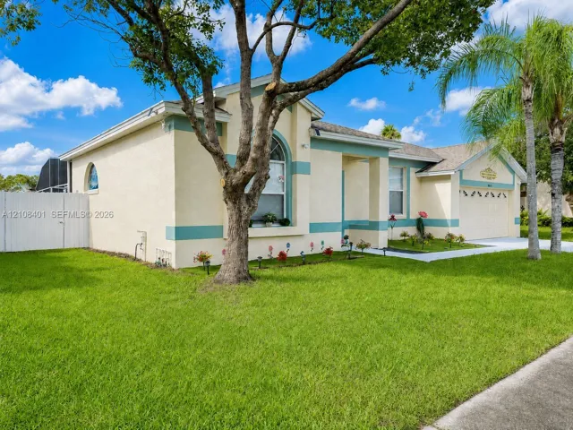 Stucco exterior featuring arched windows, a multi-car garage, and established landscaping
