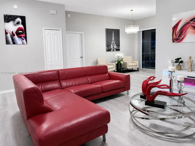 Neutral-toned living space featuring light wood-finish flooring, a drum pendant light fixture, and a built-in electric fireplace console