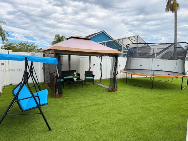 Backyard featuring synthetic turf and a full-perimeter white vinyl privacy fence