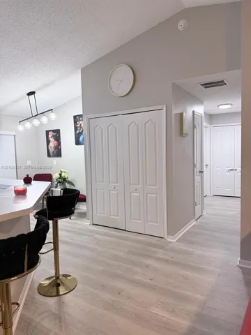 Vaulted ceilings, wood-finish flooring, white paneled closet doors, and a multi-pendant light fixture over a breakfast bar