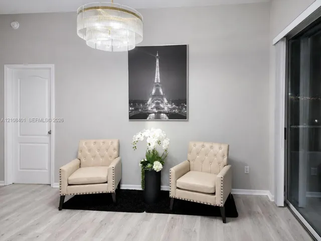 Multi-tiered drum chandelier with clear glass accents, light-toned wood-finish flooring, solid-core arched interior door, and sliding glass door