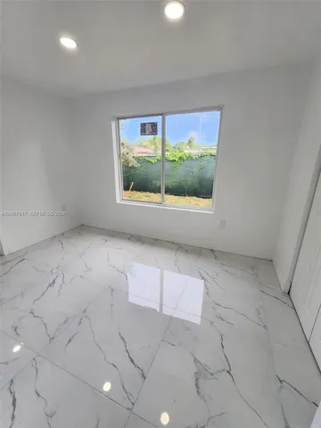 Large-format stone-finish floor tiles featuring veined detailing, recessed ceiling lighting, and a large horizontal sliding window