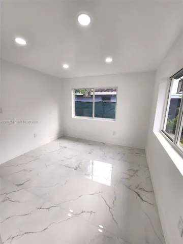 Polished stone-finish tile flooring, recessed ceiling lighting, and large-format sliding windows