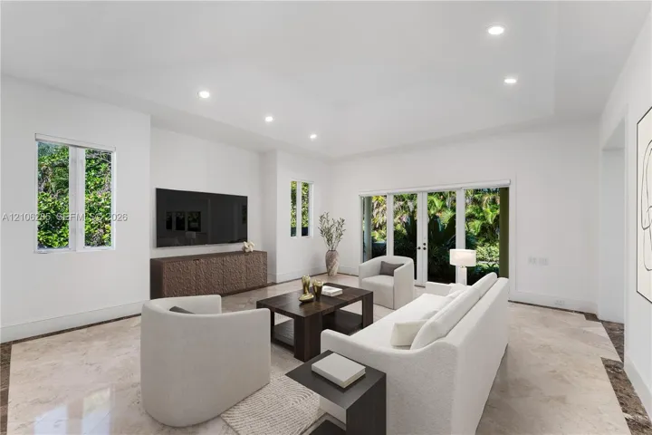 Living area featuring a tray ceiling, recessed lighting, stone flooring, and glass-paneled double doors with exterior access