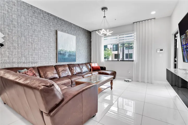 Textured accent wall, large-format tile flooring, modern multi-arm chandelier, and wall-mounted media cabinetry