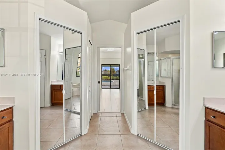 Dual mirrored sliding-door closets, tile flooring, and symmetrical cabinetry with light-toned countertops