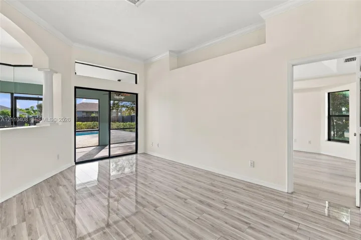 High ceilings with crown molding, wood-finish flooring, sliding glass door, transom window, and architectural column