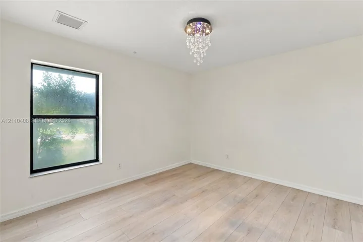 Neutral walls, wood-finish flooring, and a crystal-accented flush-mount light fixture