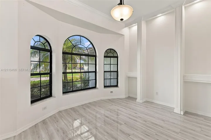 Arched windows with grid detailing, wood-finish tile flooring, built-in recessed shelving, and a decorative ceiling-mounted pendant light fixture