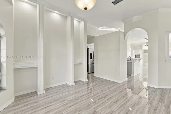 Neutral interior space featuring polished tile flooring, recessed wall niches with integrated lighting, and an arched architectural opening