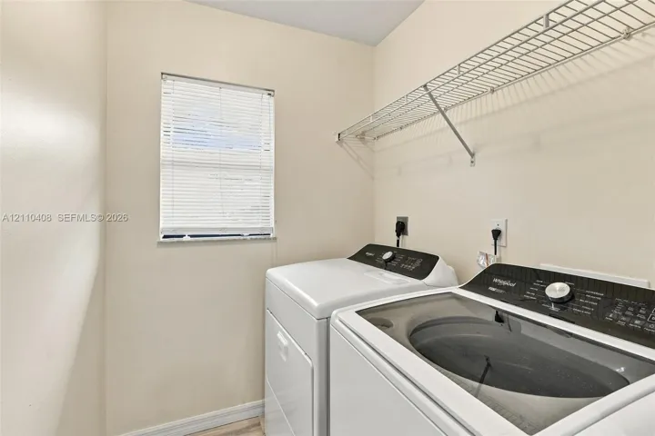 Laundry room featuring a window with horizontal blinds and integrated wire shelving