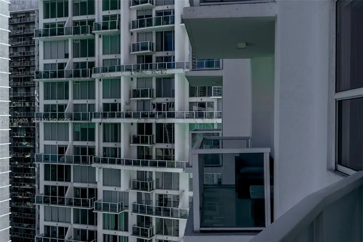 High-rise exterior featuring individual balconies with glass railings and floor-to-ceiling windows