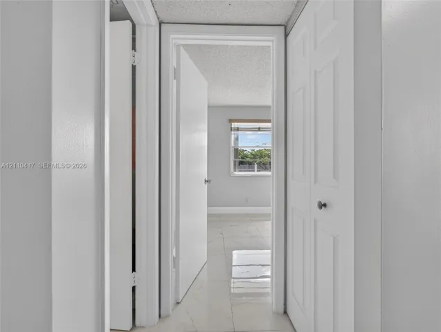 Light-colored tile flooring, white interior doors, and a double-panel closet door