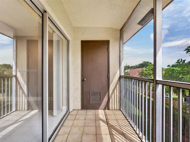 Covered balcony featuring ceramic tile flooring, a screen enclosure, metal railings, and sliding glass entry doors