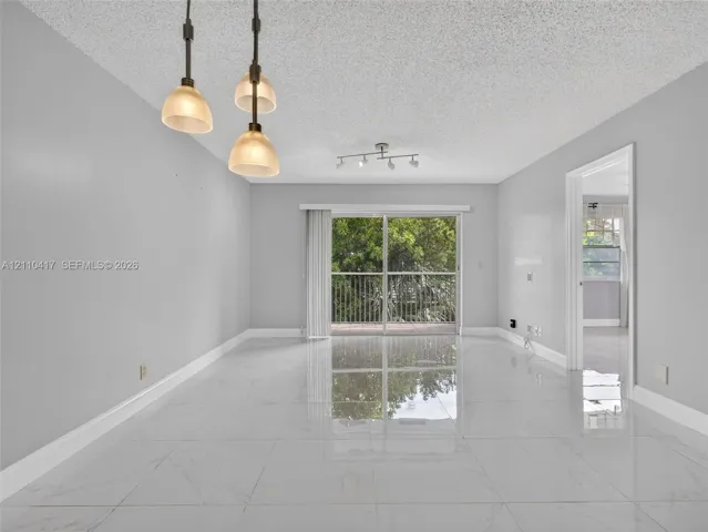 Large-format polished porcelain tile flooring, sliding glass door with balcony access, triple-pendant light fixture, and multi-directional track lighting