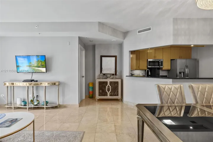Polished stone flooring, pass-through window to kitchen, neutral wall tones, and built-in stainless steel appliances
