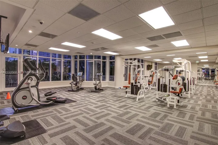Fitness center featuring floor-to-ceiling windows, patterned carpeting, and recessed ceiling lighting