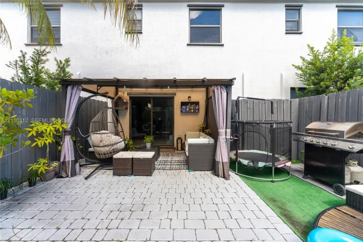 Private patio featuring interlocking concrete pavers, a built-in pergola structure, and a full-perimeter privacy fence