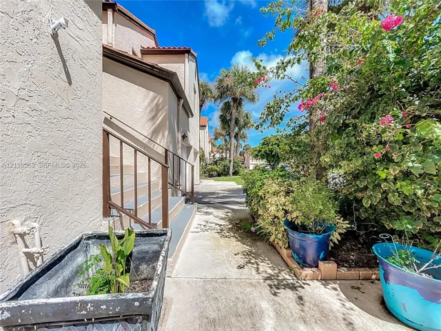 Stucco exterior featuring metal stair railings and a paved walkway