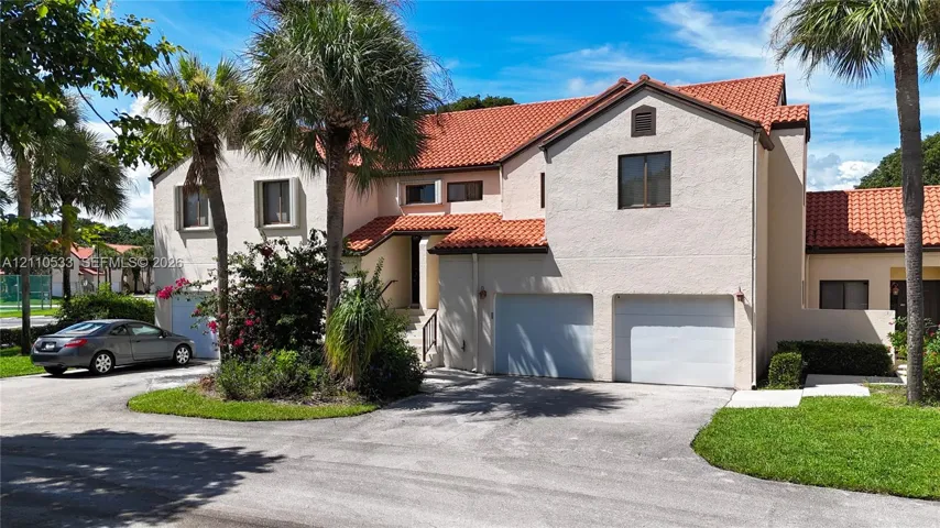 Two-story stucco exterior featuring a clay tile roof and an attached two-car garage
