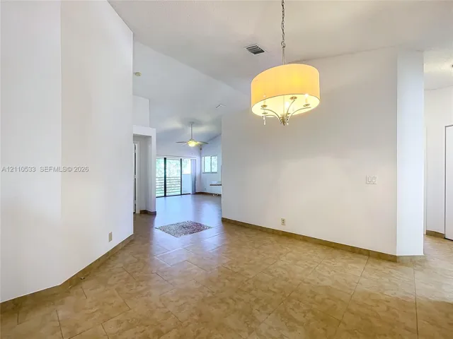 High-ceiling interior space featuring large-format tile flooring and a drum-style pendant light fixture