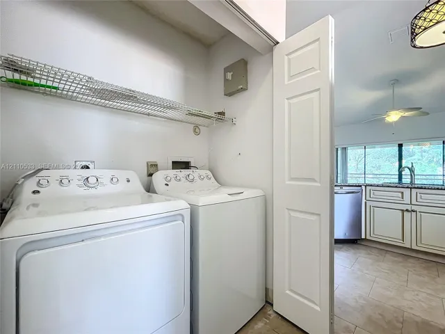 Laundry area featuring a wire-grid shelving unit and a white paneled door, with stone-finish tile flooring and cabinetry visible in the background