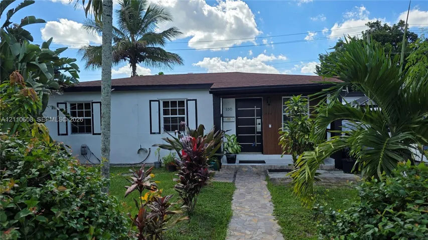 Single-story residence featuring a smooth stucco facade, asphalt shingle roof, modern entry door with horizontal glass panels, decorative exterior shutters, and a natural stone walkway