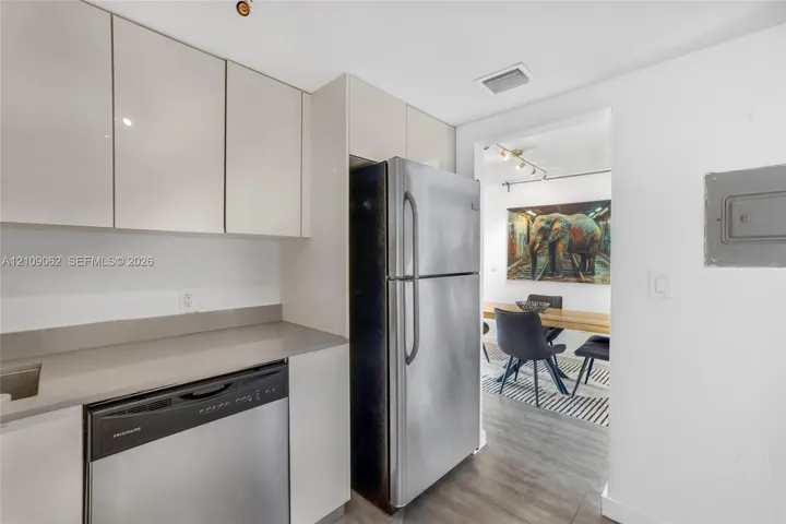 Kitchen featuring high-gloss slab cabinetry, solid-surface countertops, and full-size stainless steel appliances