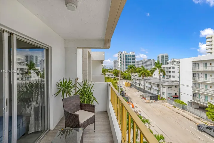 Covered balcony featuring metal railing, tile flooring, and sliding glass door access