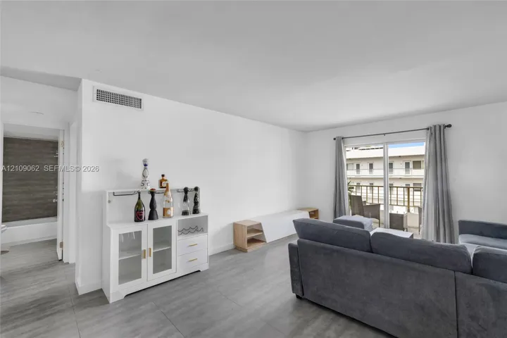 Open-concept interior featuring large-format tile flooring and a sliding glass door providing external access