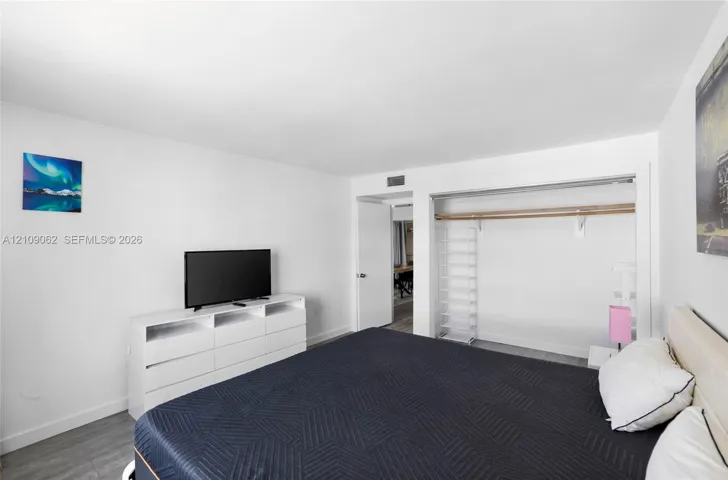 Interior space featuring wood-finish flooring, smooth wall surfaces, and a reach-in closet with integrated shelving and rod