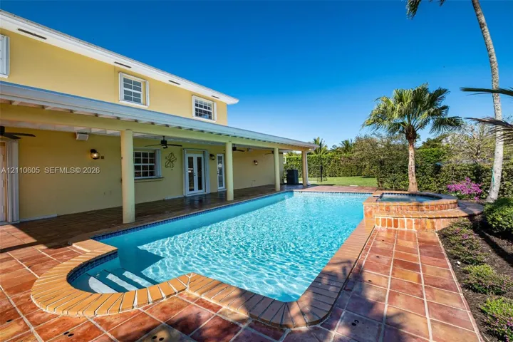 Covered patio with recessed ceiling fans, swimming pool, raised spillover spa, and terracotta-style tile decking