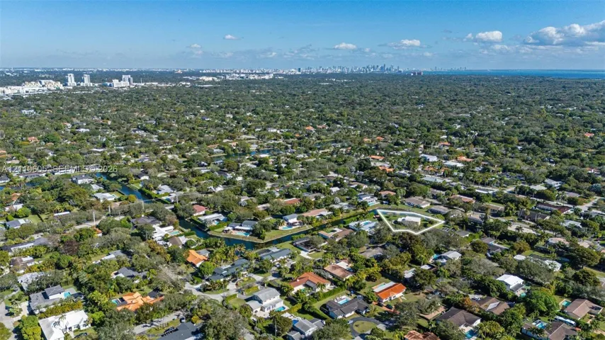 Aerial perspective of a residential property featuring a large lot, perimeter landscaping, and proximity to a canal