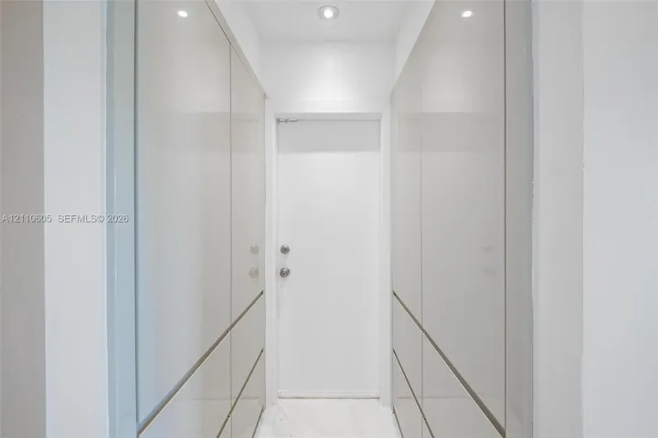 Floor-to-ceiling high-gloss cabinetry with integrated hardware, recessed ceiling lighting, and stone-finish flooring