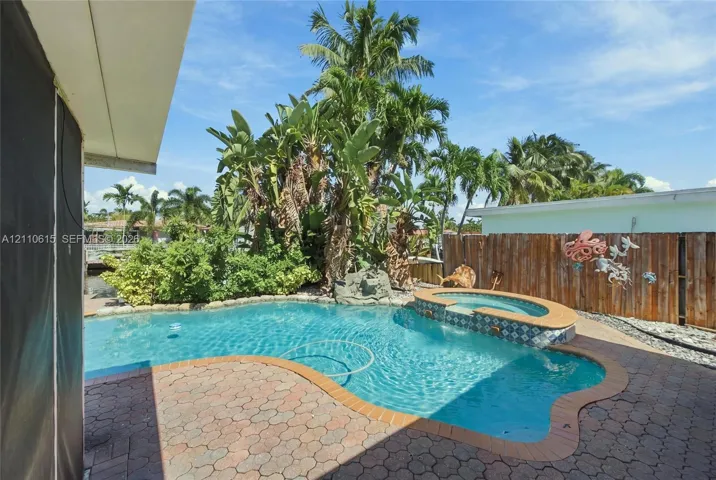 In-ground swimming pool featuring a spillover spa with patterned tile inlay and surround pavers