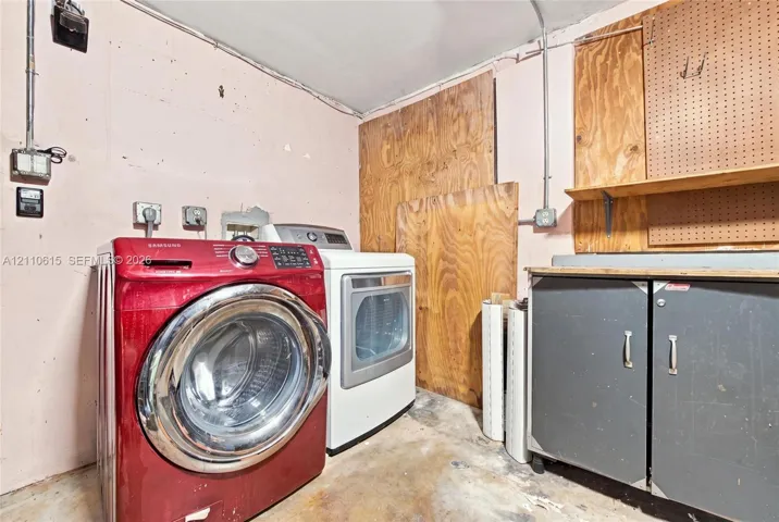 Laundry area featuring built-in metal cabinetry, wall-mounted pegboard storage, and plywood wall paneling