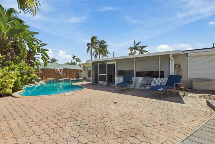 Outdoor living area featuring a paved brick patio, an in-ground swimming pool, privacy fencing, and mature landscaping