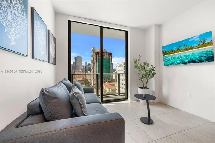 Floor-to-ceiling glass sliding door, balcony access, tile flooring, and urban cityscape backdrop