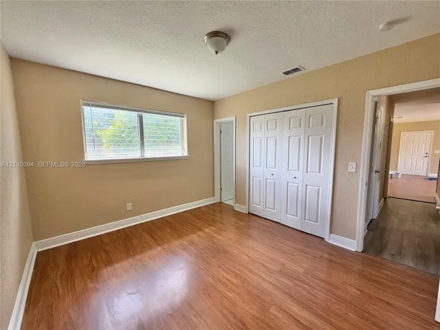 Room featuring wood-finish flooring, a horizontal sliding window, and a four-panel bi-fold closet door