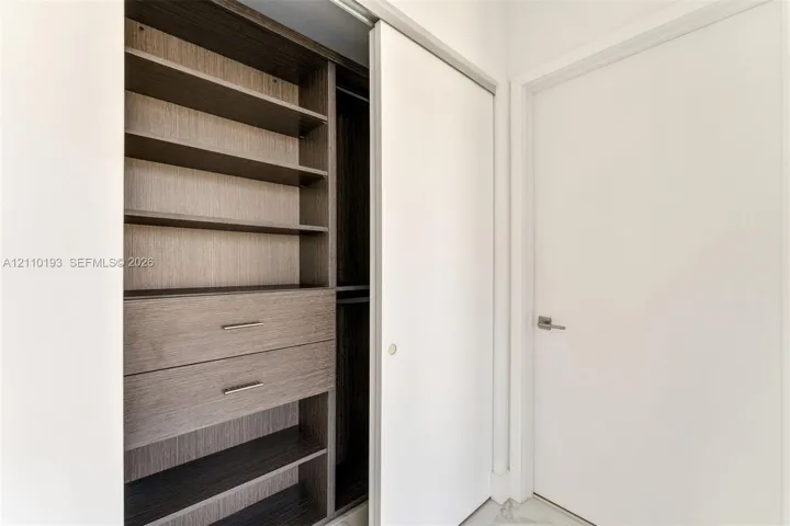 Built-in closet system featuring dark wood-finish shelving, two integrated storage drawers with metal hardware, a hanging rod, and a white sliding door